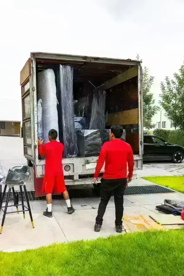 Dos cargadores HGR junto a la caja abierta del camión, cargada con muebles protegidos